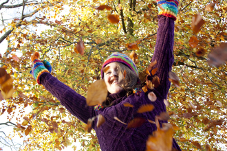 Child throwing autumn leaves into air