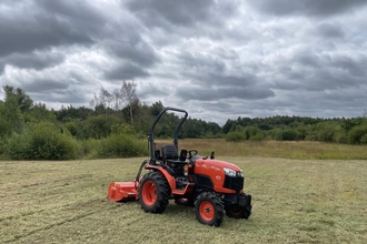 Red tractor mower on a grassland area at Whisby