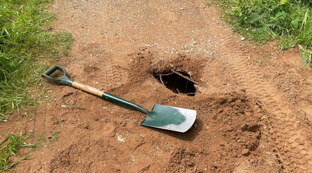 Spade next to a hole in the path created by wildlife at Whisby Nature Park